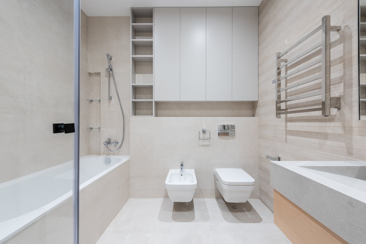 Interior of modern light bathroom with toilet and bidet next to bathtub and sink