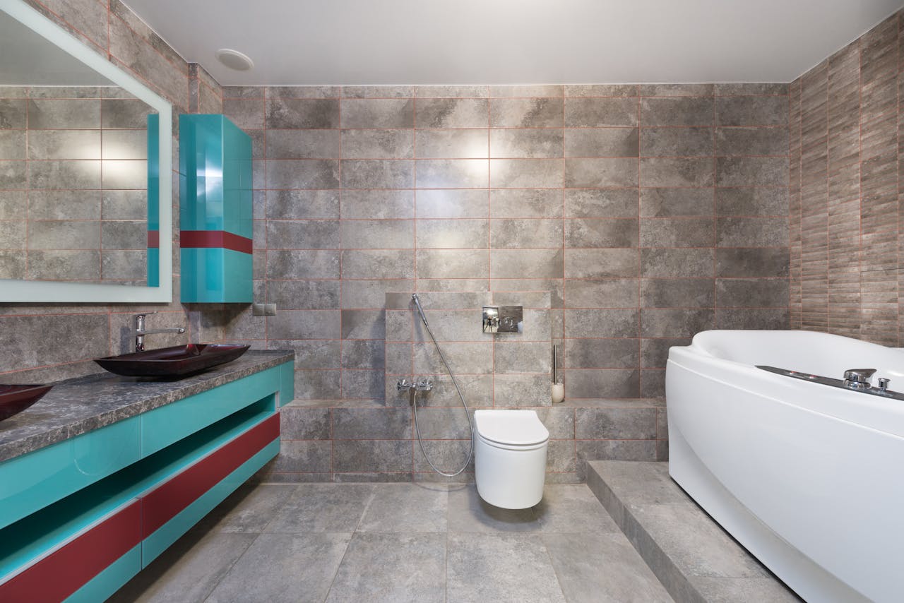 Interior of contemporary bathroom with modern toilet and bathtub with mirror hanging above sink